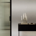 Schrank mit Dekoration, Schiebetür und Wandpaneel in Edelstahl-Metalloptik im Hintergrund