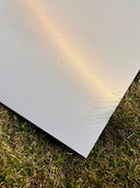 Wandpaneel in Metalloptik Edelstahl liegt auf einer Wiese.