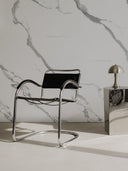 Moderner Stuhl mit Beistelltisch in Chrome und Lampe vor Wandpaneel in Marmoroptik Calacatta Weiß