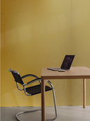 Goldenes Metall-Wandpaneel im Arbeitsbereich mit Stuhl, Tisch und Laptop