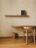 Softstone Wandpaneel, Creme, installiert an der Wand, mit Regalen an der Oberfläche, davor ein Stuhl