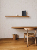 Softstone Wandpaneel Off-White mit Regalen an der Wand, davor Stuhl