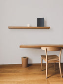 Softstone Wandpaneel, Weiss, installiert an der Wand, mit Regalen an der Oberfläche, davor ein Stuhl