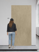 Eine junge Frau steht vor einem Wandpaneel in Steinoptik Beige.